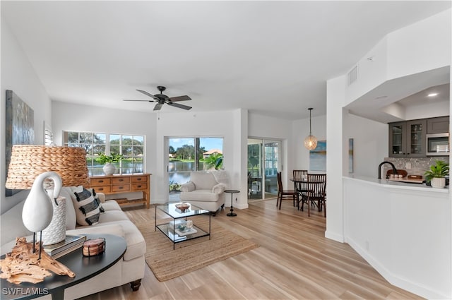 living room with light wood-type flooring, sink, and ceiling fan