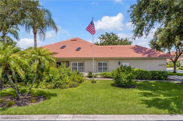 rear view of house with a lawn, a tiled roof, and stucco siding