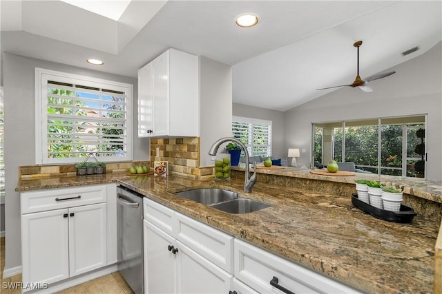 kitchen featuring visible vents, white cabinetry, vaulted ceiling, a sink, and dark stone counters