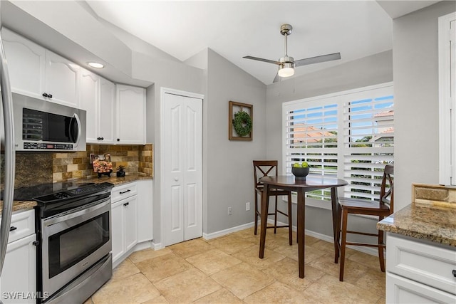 kitchen featuring stainless steel appliances, white cabinetry, vaulted ceiling, decorative backsplash, and light stone countertops