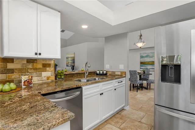 kitchen featuring decorative backsplash, appliances with stainless steel finishes, white cabinetry, a sink, and dark stone countertops