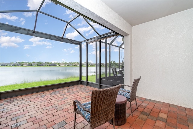 view of patio with glass enclosure and a water view