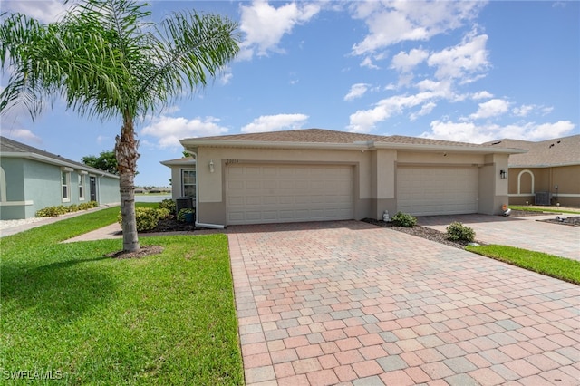 view of front of home with cooling unit, a front lawn, and a garage