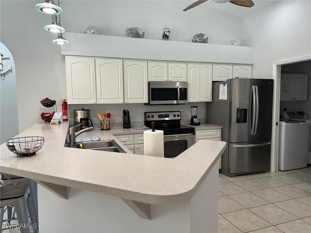 kitchen with kitchen peninsula, ceiling fan, hanging light fixtures, washer / dryer, and appliances with stainless steel finishes