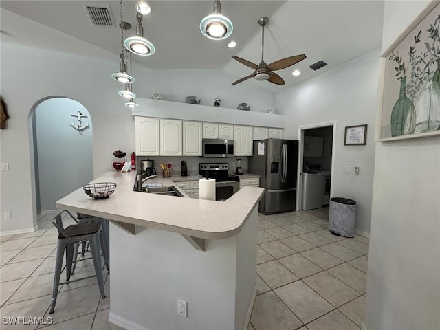 kitchen with appliances with stainless steel finishes, decorative light fixtures, washer and dryer, and ceiling fan