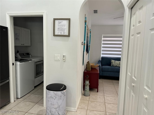 kitchen featuring washer and clothes dryer, light tile patterned floors, and black fridge