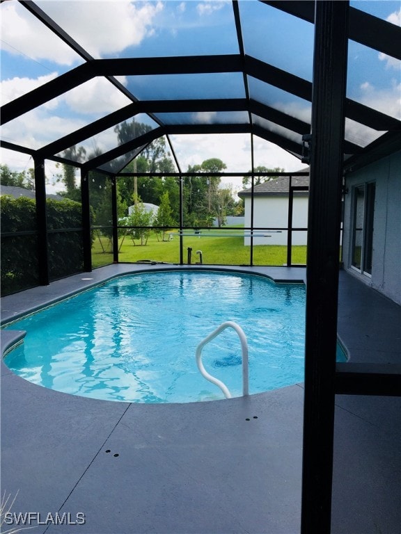 view of swimming pool with a lawn, a patio, and a lanai