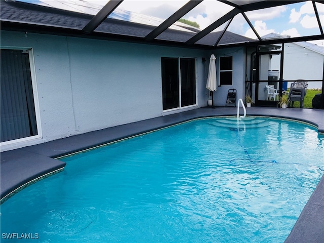 view of swimming pool with glass enclosure and a patio