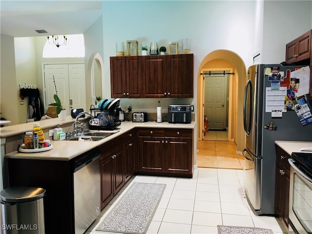 kitchen featuring a notable chandelier, light tile patterned floors, stainless steel appliances, sink, and kitchen peninsula