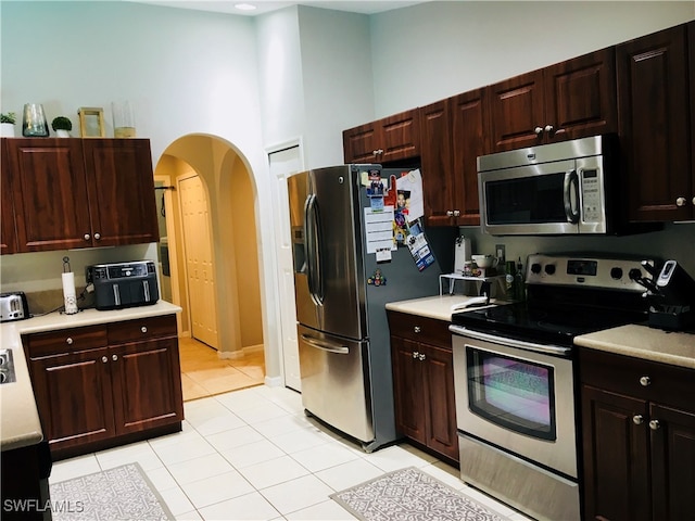 kitchen featuring light tile patterned floors, stainless steel appliances, and a high ceiling