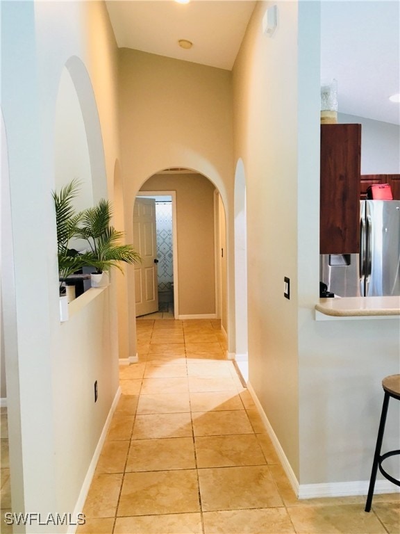 corridor with light tile patterned floors and vaulted ceiling