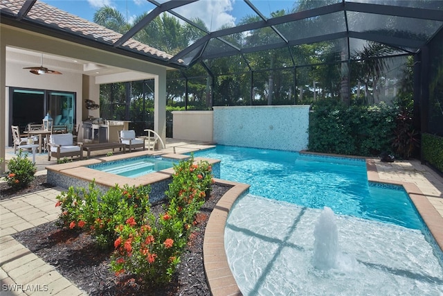 view of swimming pool featuring an in ground hot tub, pool water feature, a patio, ceiling fan, and glass enclosure