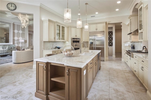 kitchen featuring a kitchen island with sink, cream cabinetry, decorative light fixtures, sink, and light stone countertops