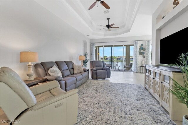 living room with a tray ceiling, light tile patterned floors, and ceiling fan