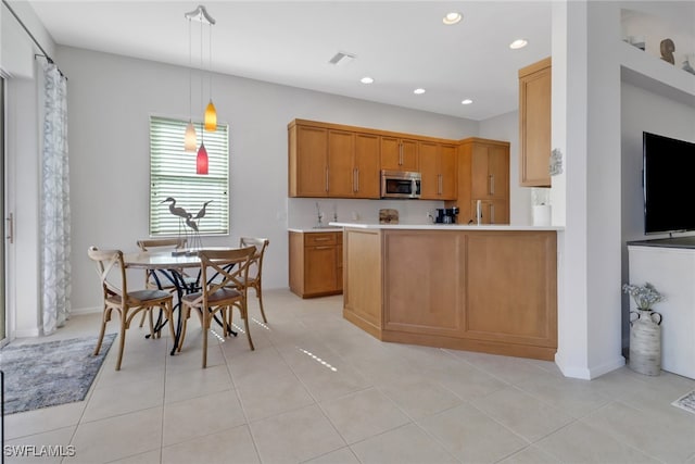 kitchen featuring kitchen peninsula, decorative light fixtures, and light tile patterned flooring