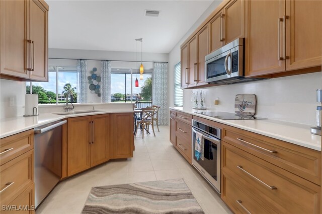 kitchen with light tile patterned floors, decorative light fixtures, stainless steel appliances, and sink