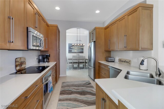 kitchen with a notable chandelier, stainless steel appliances, sink, hanging light fixtures, and light tile patterned flooring