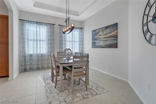 tiled dining space with a tray ceiling, ornamental molding, a wealth of natural light, and an inviting chandelier