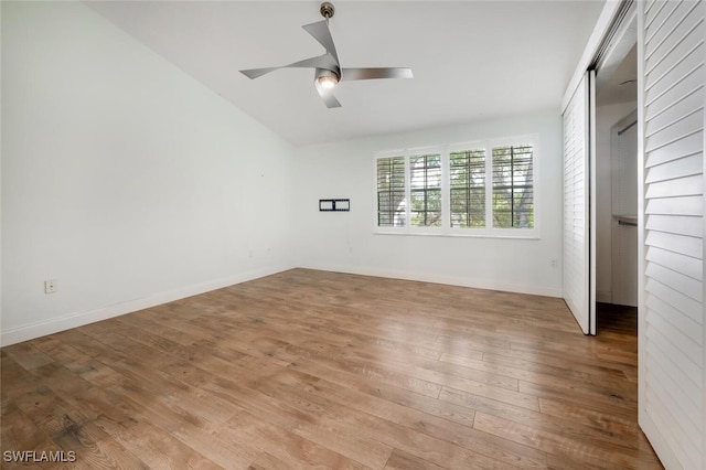 unfurnished bedroom with a closet, baseboards, vaulted ceiling, and wood finished floors