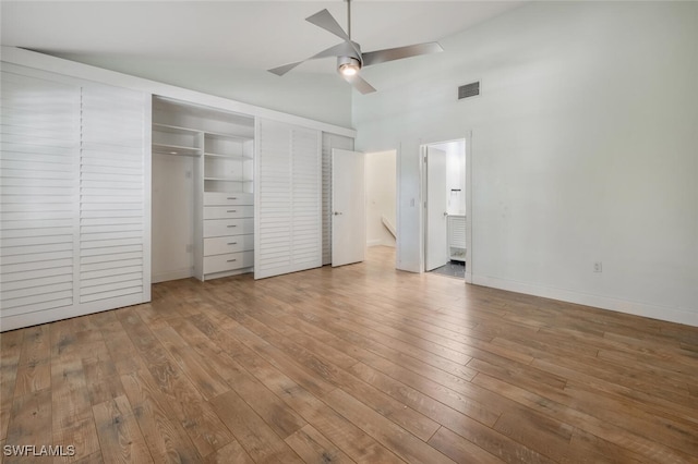 unfurnished bedroom featuring visible vents, hardwood / wood-style floors, a ceiling fan, high vaulted ceiling, and baseboards