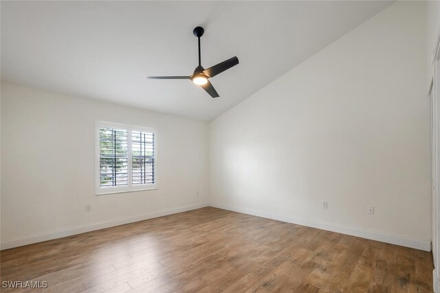 empty room featuring lofted ceiling, ceiling fan, wood finished floors, and baseboards