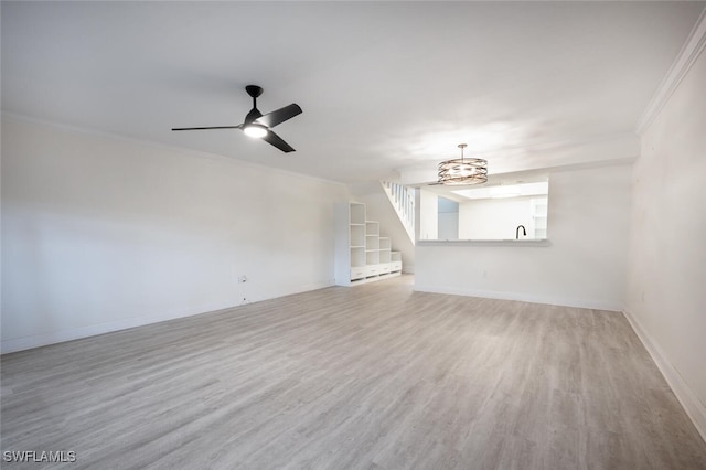 unfurnished living room with a ceiling fan, crown molding, baseboards, and wood finished floors