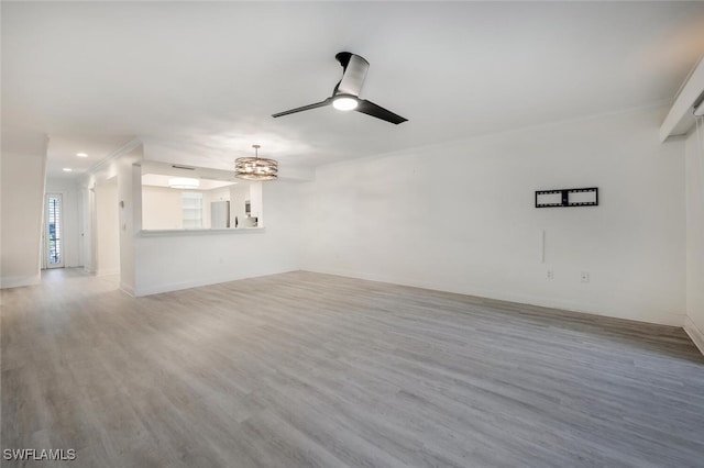 unfurnished living room with baseboards, wood finished floors, and ceiling fan with notable chandelier