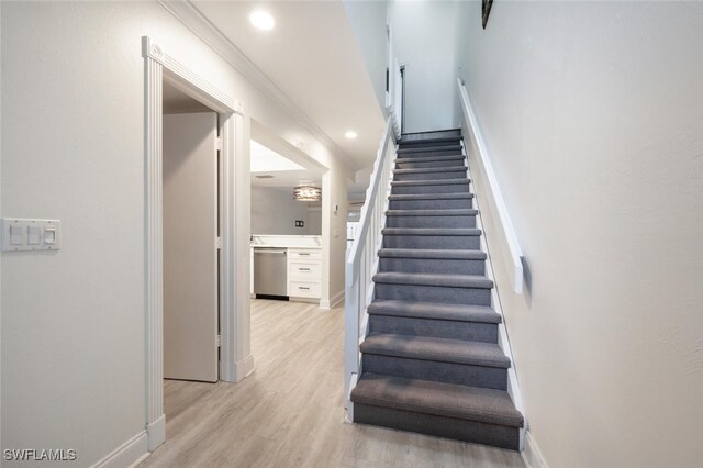 stairs featuring wood-type flooring and ornamental molding