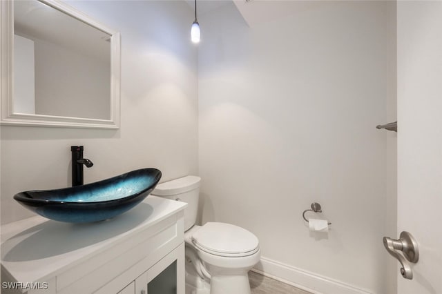 bathroom with baseboards, vanity, toilet, and wood finished floors