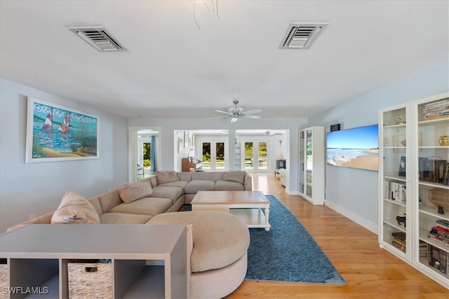 living room featuring light wood-type flooring, ceiling fan, and french doors