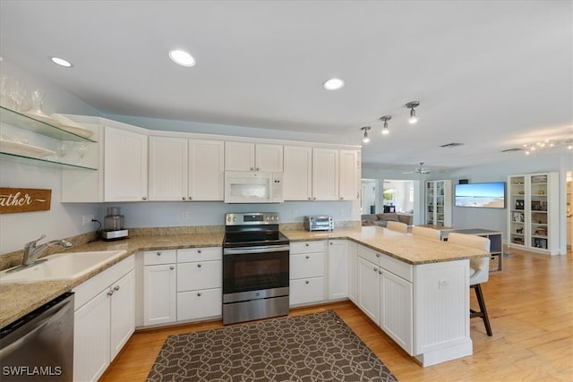 kitchen featuring white cabinetry, a breakfast bar, kitchen peninsula, stainless steel appliances, and light hardwood / wood-style flooring