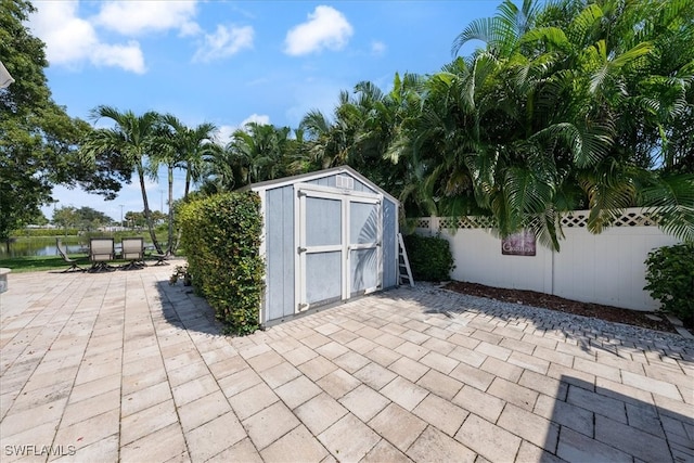 view of patio / terrace featuring a storage unit and a water view