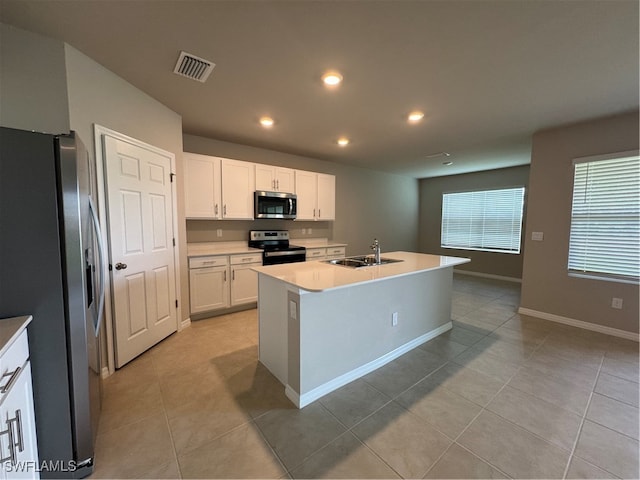 kitchen with white cabinetry, stainless steel appliances, an island with sink, sink, and light tile patterned flooring