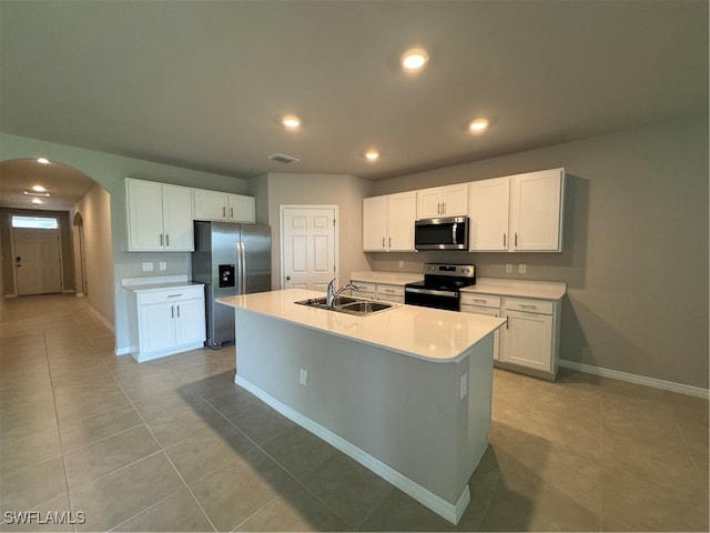 kitchen featuring white cabinets, light tile patterned floors, stainless steel appliances, sink, and an island with sink