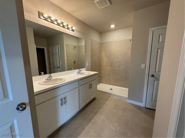 bathroom with vanity, tiled shower, and tile patterned flooring