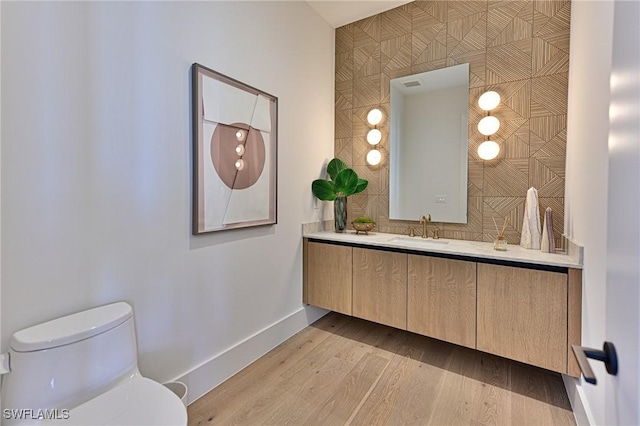 bathroom featuring wood-type flooring, vanity, and toilet