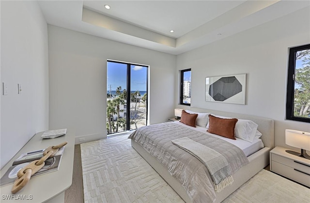 bedroom with access to outside and a raised ceiling