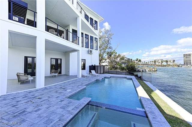 view of swimming pool featuring an in ground hot tub, french doors, a water view, and a patio area