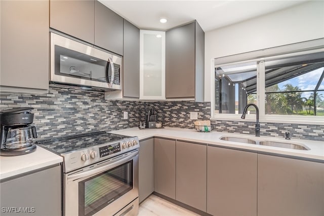 kitchen featuring gray cabinetry, sink, appliances with stainless steel finishes, and tasteful backsplash