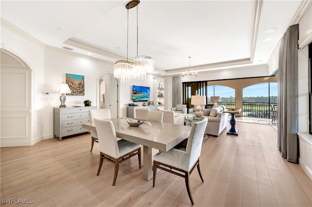 dining space featuring light hardwood / wood-style floors, crown molding, a chandelier, and a tray ceiling