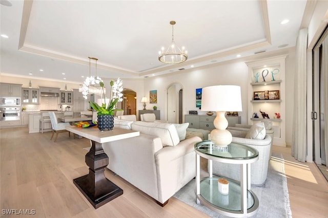 living room featuring light hardwood / wood-style floors, an inviting chandelier, and a tray ceiling