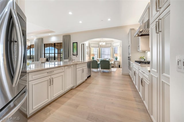 kitchen with light hardwood / wood-style floors, a healthy amount of sunlight, stainless steel appliances, and light stone countertops