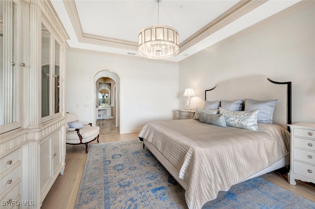 bedroom with an inviting chandelier, light hardwood / wood-style flooring, and a tray ceiling