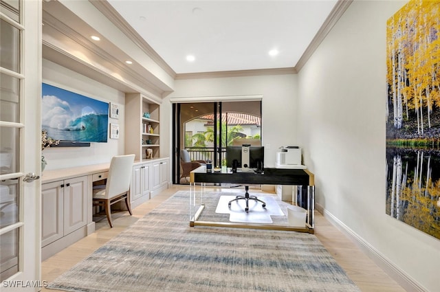 office with built in desk, ornamental molding, built in shelves, and light hardwood / wood-style floors