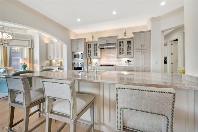 kitchen with ornamental molding, stainless steel appliances, sink, and light wood-type flooring