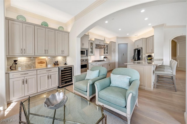 living room featuring sink, light hardwood / wood-style flooring, crown molding, and beverage cooler