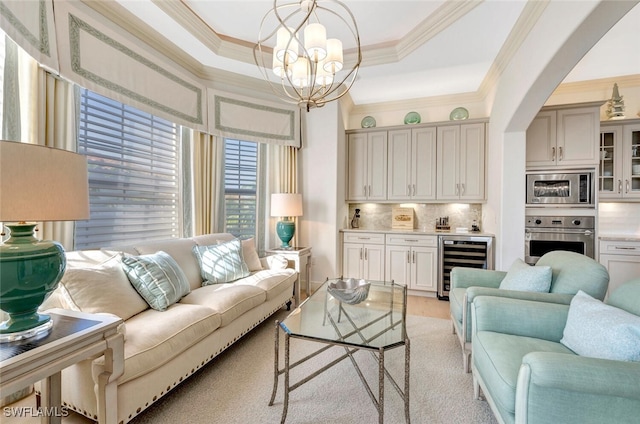 living room with wine cooler, a chandelier, crown molding, and a tray ceiling