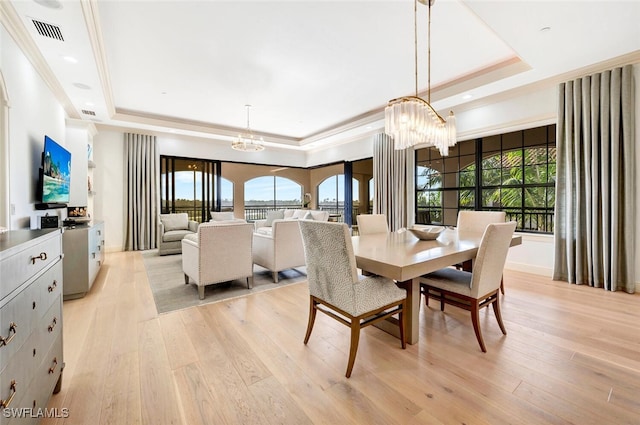 dining room featuring a chandelier, a healthy amount of sunlight, and a raised ceiling