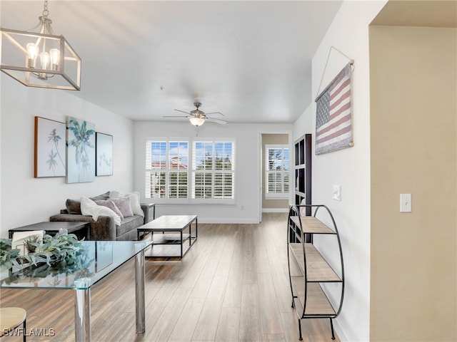 living room featuring wood-type flooring and ceiling fan with notable chandelier