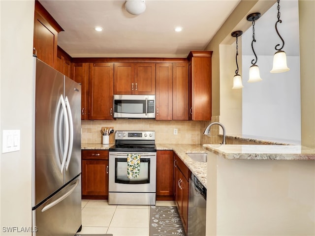 kitchen featuring decorative light fixtures, kitchen peninsula, sink, appliances with stainless steel finishes, and light stone counters